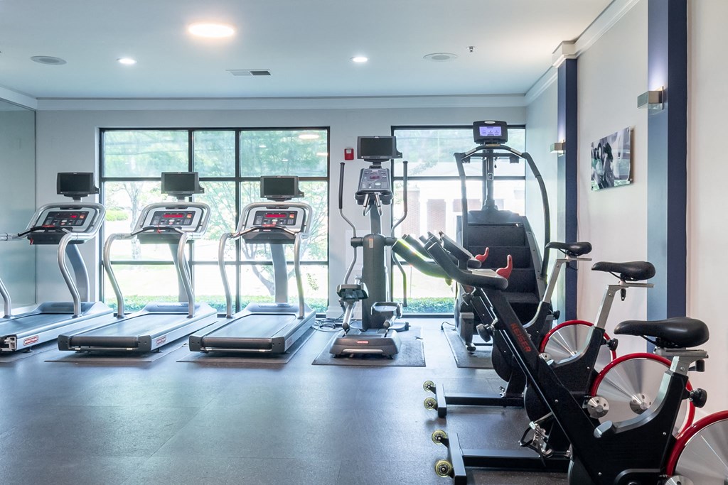 a gym with cardio equipment and a large window