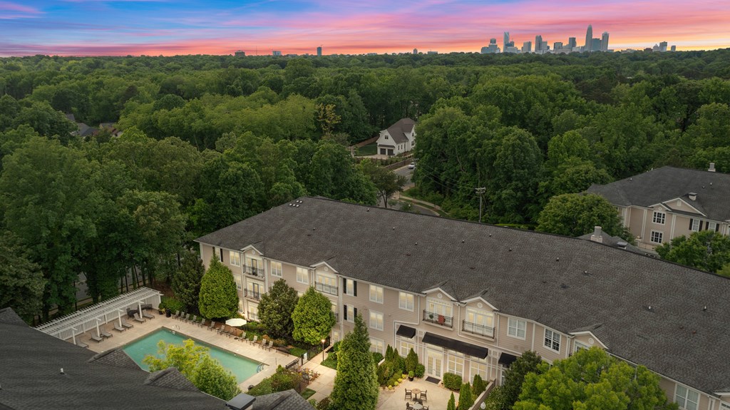 an aerial view of a house with a swimming pool and trees and a city skyline
