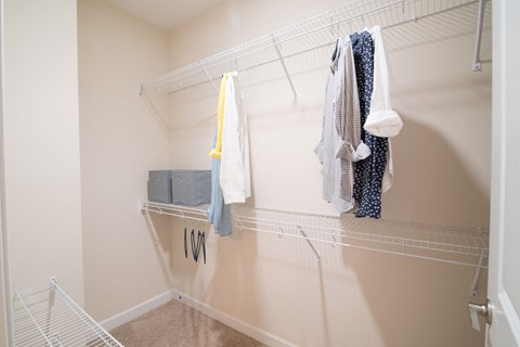 a spacious walk in closet in a home with clothes hanging on a rack