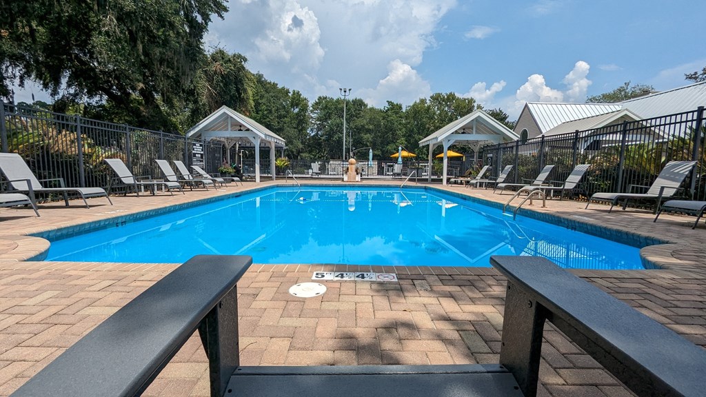 a swimming pool with lounge chairs and umbrellas