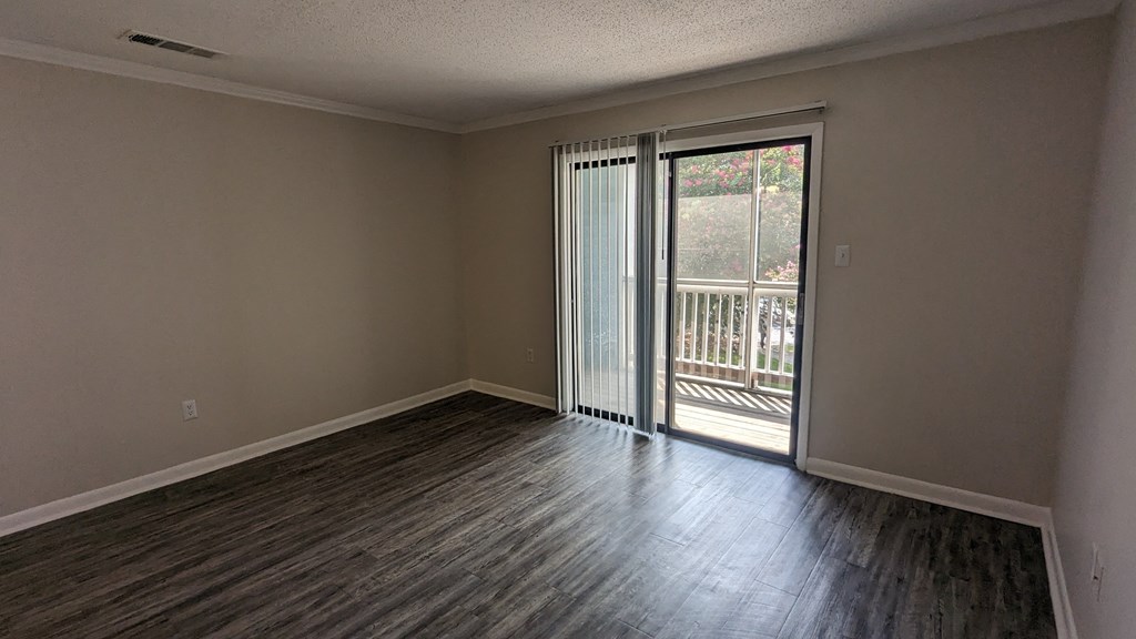 an empty living room with a sliding glass door leading to a balcony