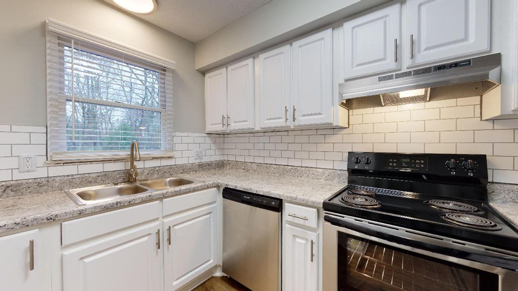 a kitchen with white cabinets and a stove and a sink