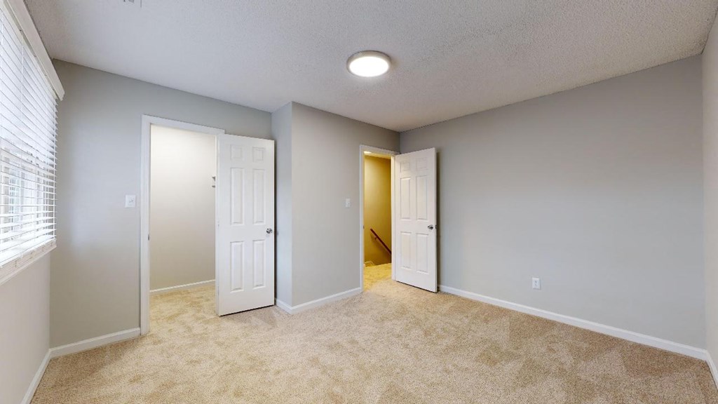 an empty room with a door to a hallway and a closet
