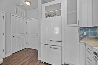 a white kitchen with white cabinets and a white refrigerator