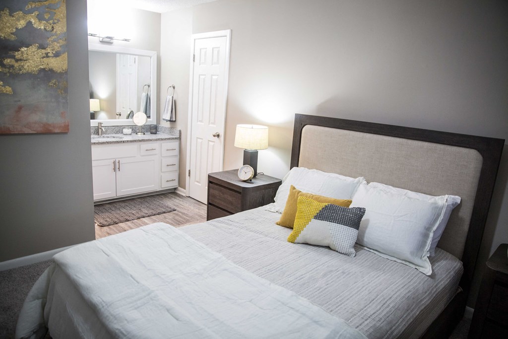 a bedroom with a large bed and a bathroom in the background