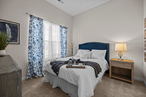 a bedroom with a bed and a window with blue and white curtains