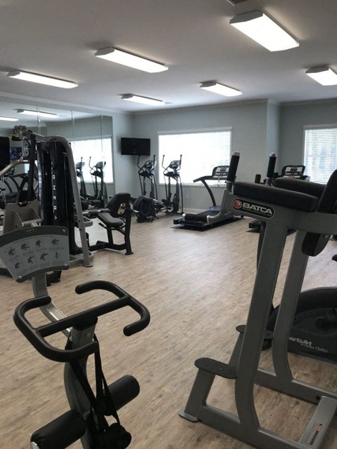 a gym with various exercise equipment on the floor and mirrors