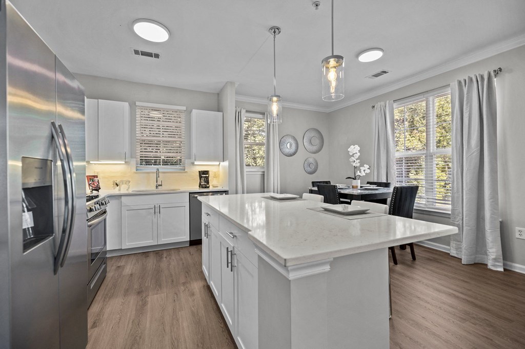 a white kitchen with a large island and a dining room