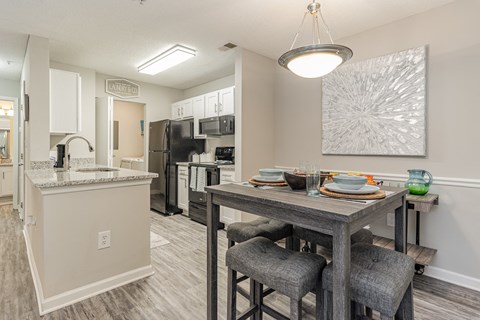 A modern kitchen with a dining table set for two.
