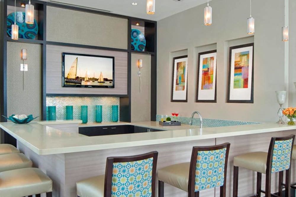 a bar in a hotel room with chairs and a sink