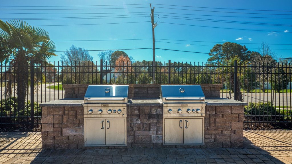 two gas bbqs in front of a stone wall with a fence  at Bayville Apartments, Virginia, 23455
