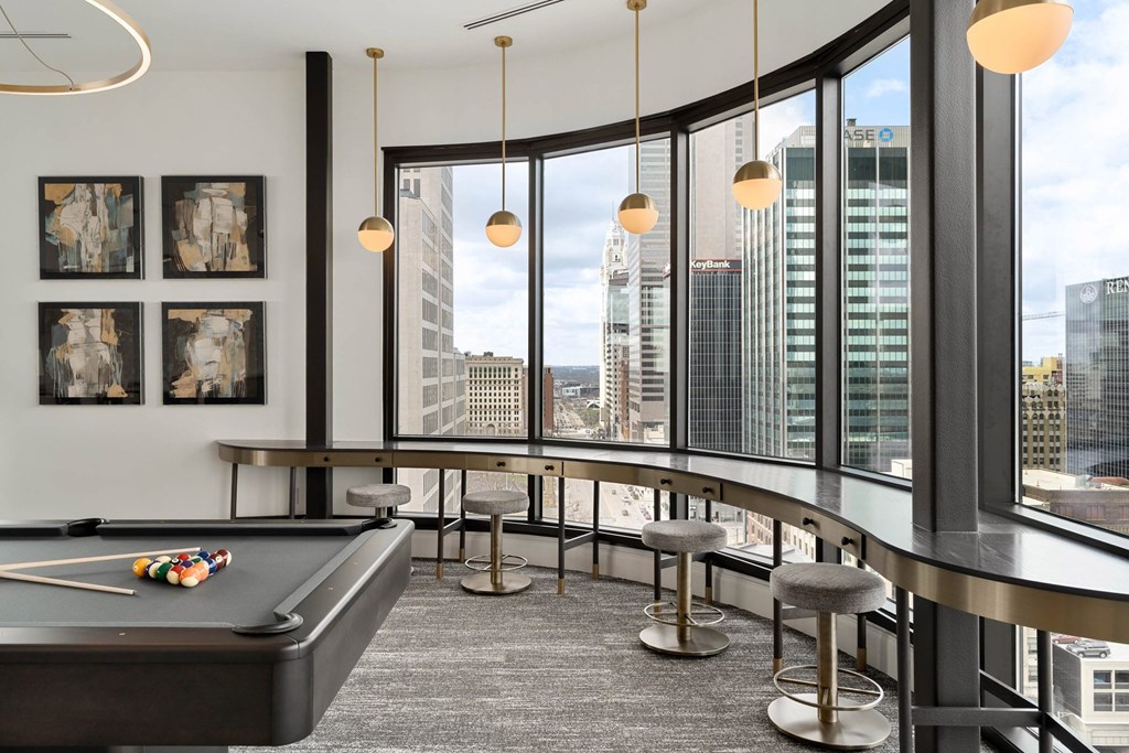A billiard table is in the middle of a room with a view of the city.