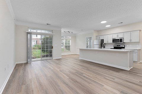 A kitchen with white cabinets and a white countertop with a refrigerator, microwave, and oven.