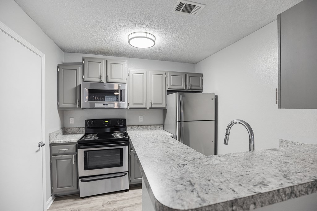 a kitchen with granite counter tops and stainless steel appliances at Midtown Crossing in Raleigh, NC