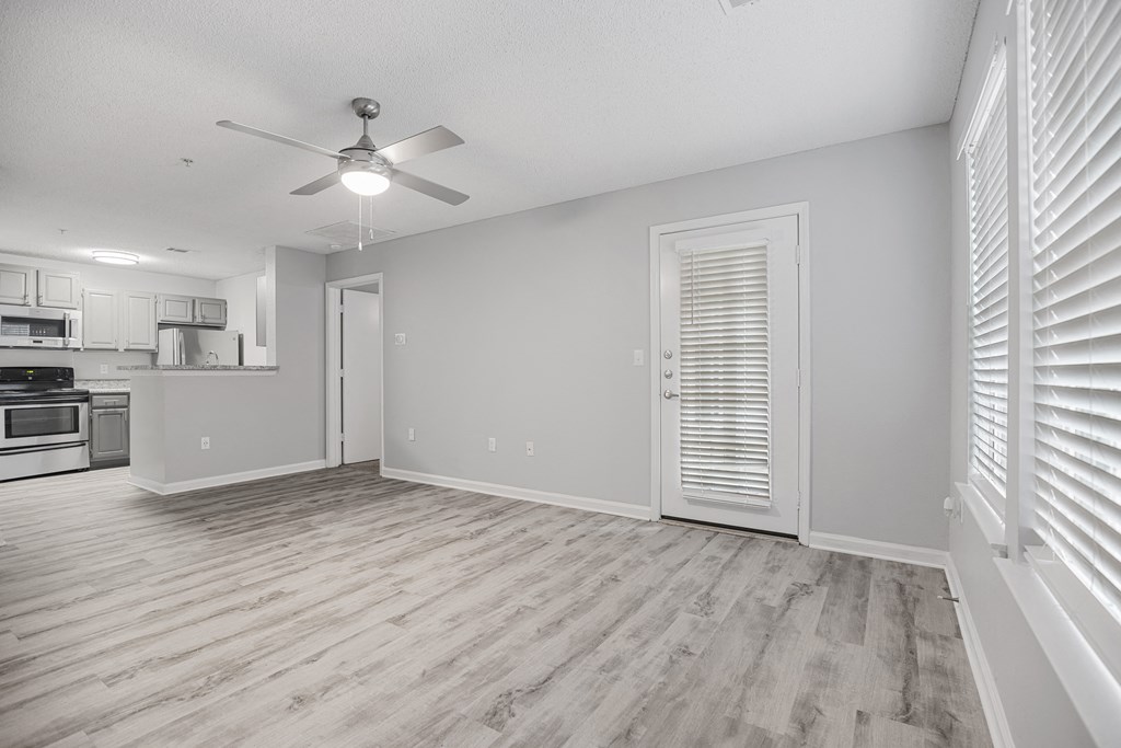 an empty living room with a ceiling fan and a kitchen at Midtown Crossing in North Carolina 27609