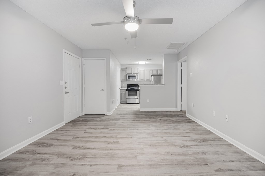an empty living room with a ceiling fan and a kitchen at Midtown Crossing in Raleigh, 27609