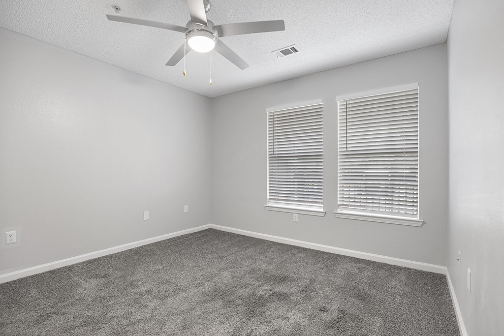 an empty room with a ceiling fan and two windows at Midtown Crossing in Raleigh, 27609