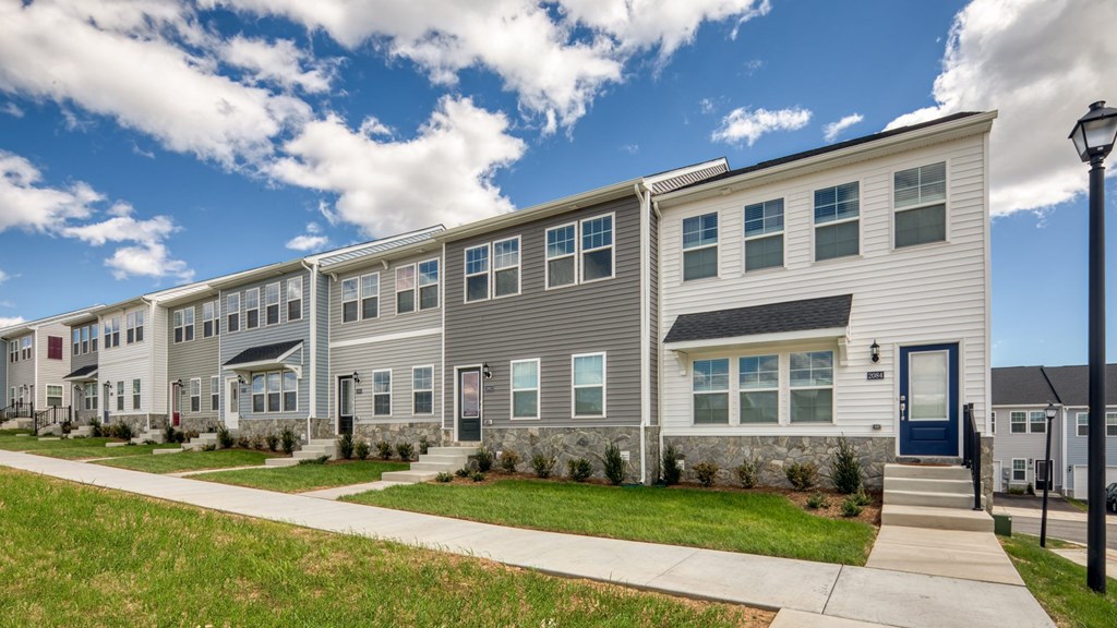 A row of modern townhouses with a sidewalk in front at The Mark Townhomes Apartments, Harrisonburg, Virginia