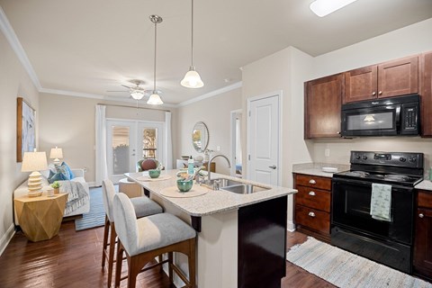 A kitchen with a black stove and wooden cabinets.