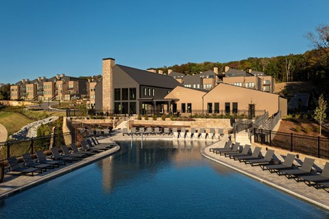 A large swimming pool with lounge chairs and a building in the background.