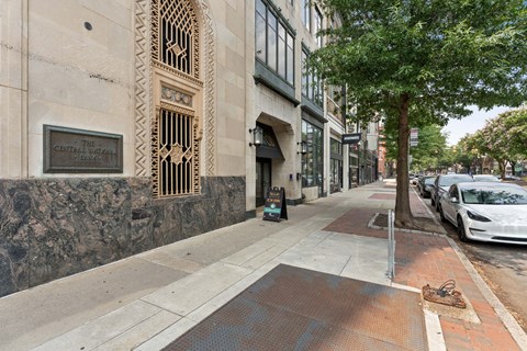 a sidewalk with a tree and cars parked on the side of the road