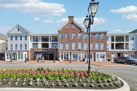 A street view of a town with buildings, cars, and a flower bed.