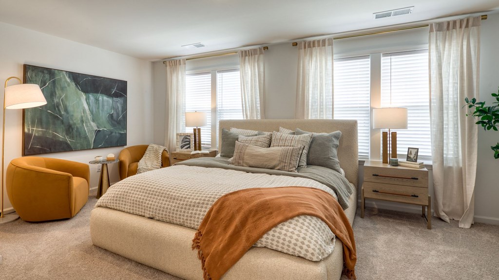 A bedroom with a large bed and a painting on the wall at The Mark Townhomes Apartments, Harrisonburg, VA