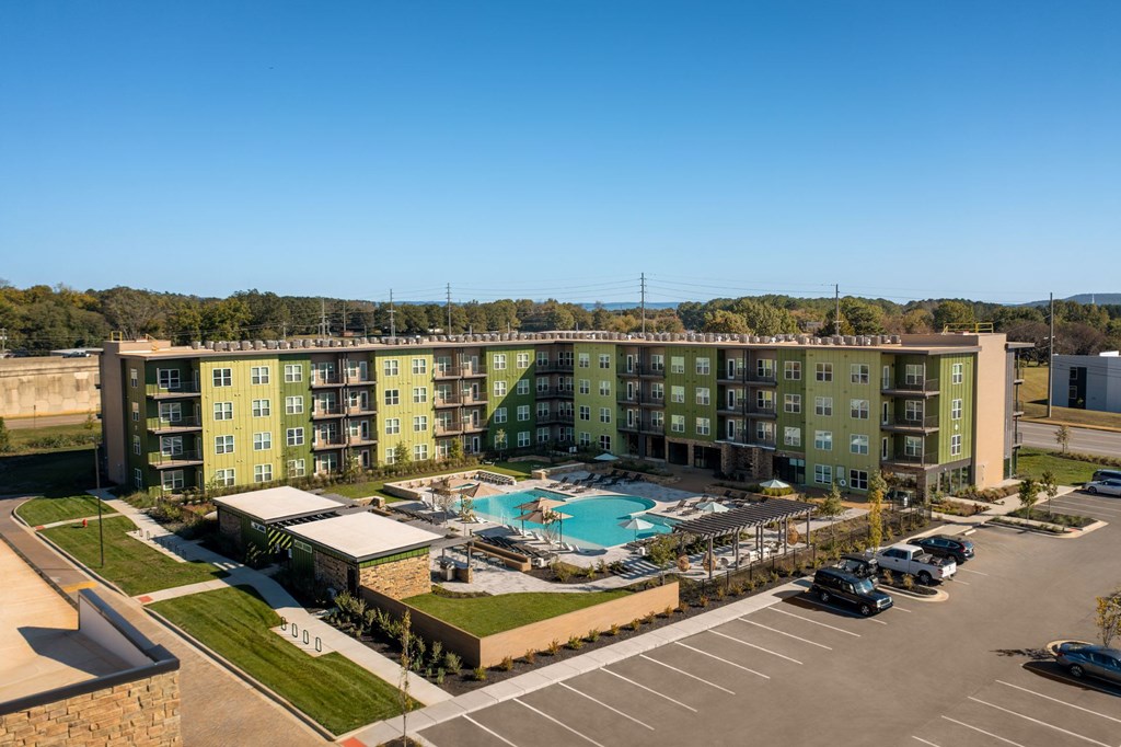 A large apartment complex with a pool in the middle of the parking lot.