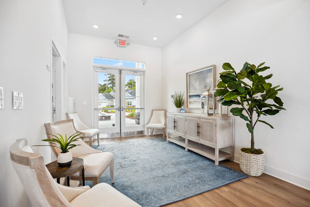 a living room with white walls and white chairs and a blue rug