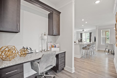 A modern kitchen with a grey chair and wooden cabinets.