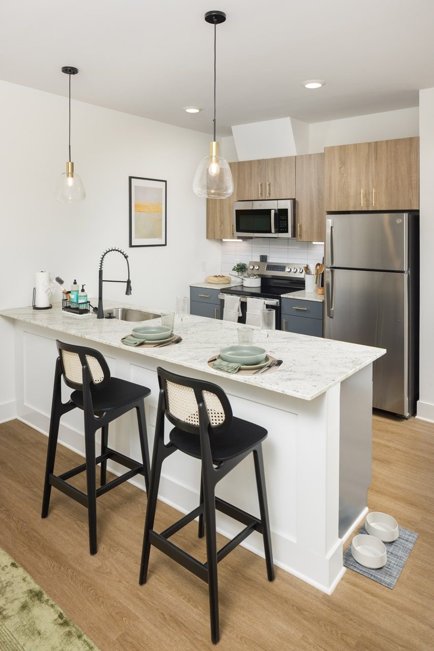 A kitchen with a white countertop and black barstools.