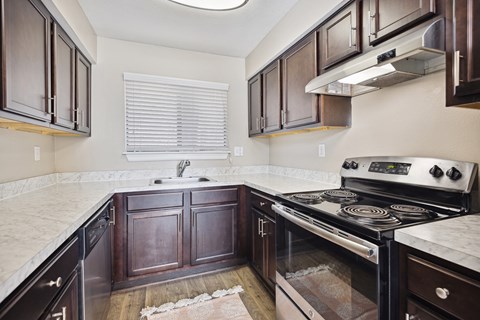 A kitchen with a black stove top oven and wooden cabinets.