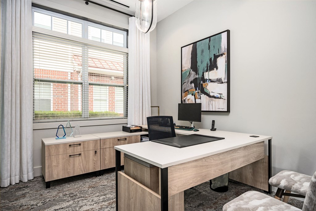 A modern home office with a laptop on the desk and a painting on the wall.