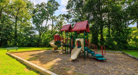 A playground with a red roofed structure and a green slide.
