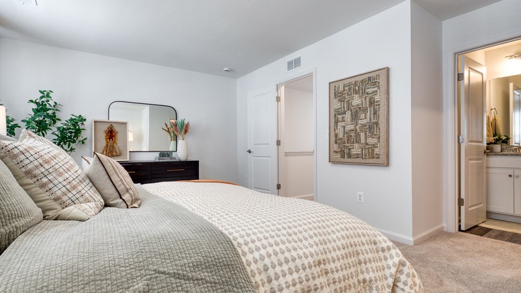 A bedroom with a large bed and a mirror on the wall at The Mark Townhomes Apartments, Harrisonburg