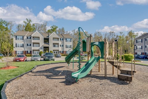 A playground with a green slide and a wooden structure.
