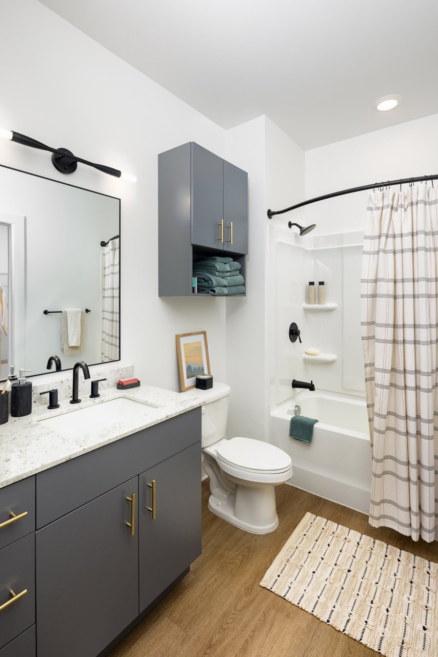 A bathroom with a white toilet, sink, and a shower with a white curtain.