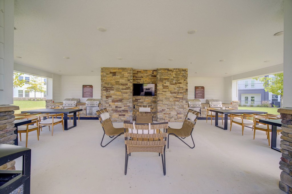 A room with a stone fireplace and chairs around a table.