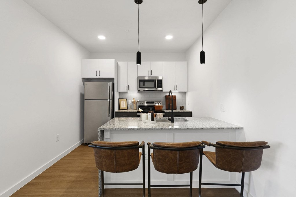 A kitchen with a refrigerator, microwave, and two chairs. at Terraces at High Mountain, Huntsville, AL, 35811
