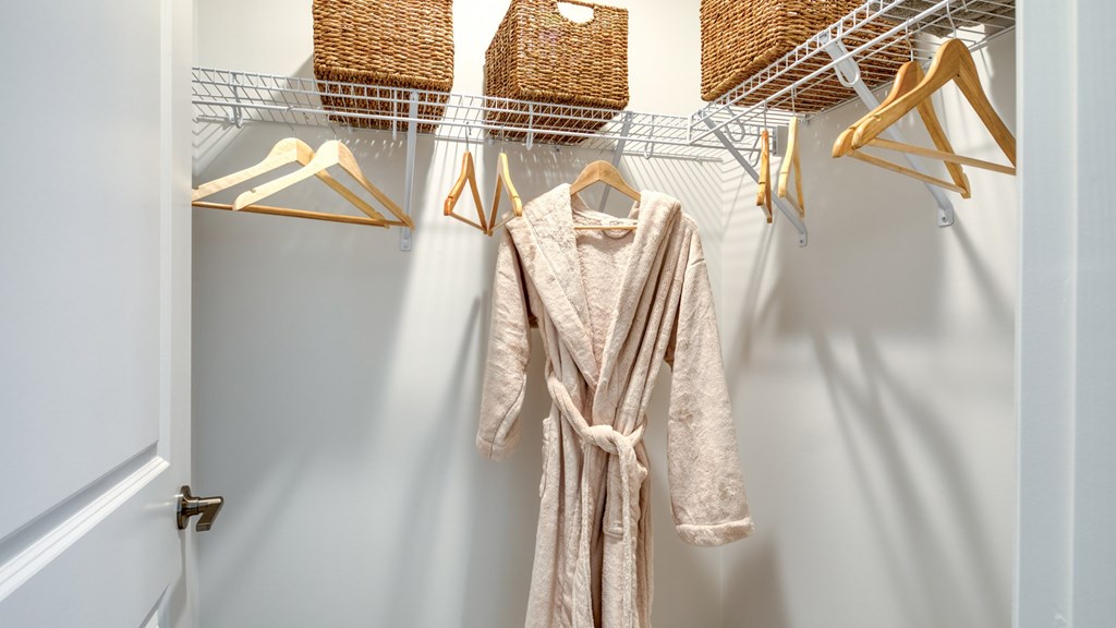 A white closet with a robe hanging on a hanger at The Mark Townhomes Apartments, Harrisonburg, Virginia