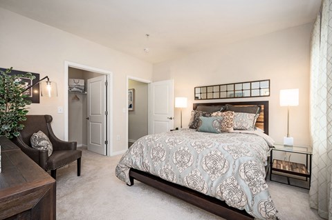 A bedroom with a large bed and a chair.