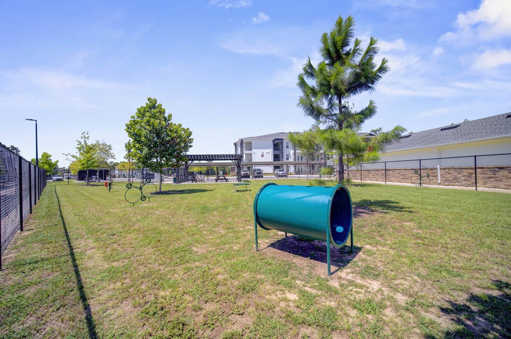 A green cylindrical object is placed on a grassy field.