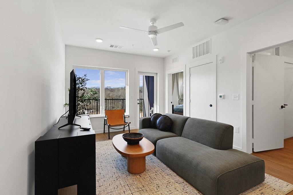 A living room with a grey couch and a television. at Terraces at High Mountain, Alabama