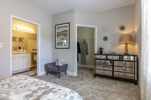A bedroom with a grey carpet and a grey bed.