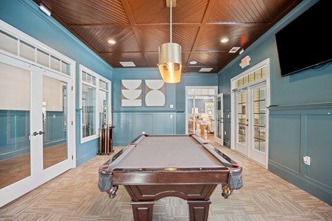 A pool table is in the middle of a room with a wooden ceiling.