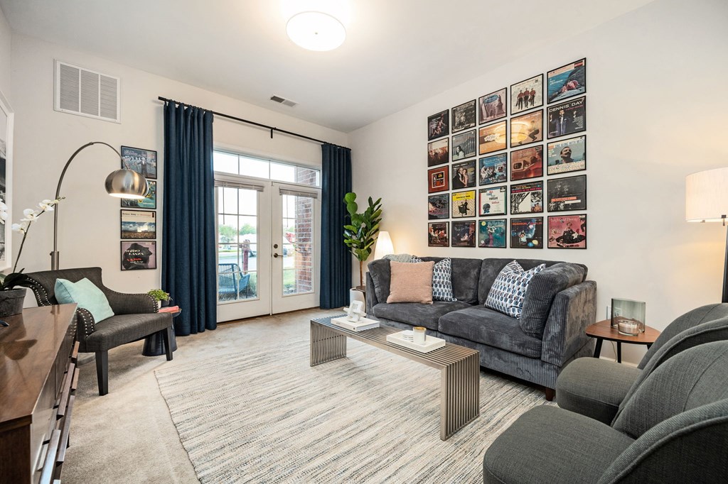 A living room with a grey couch, a coffee table, and a wall with pictures.