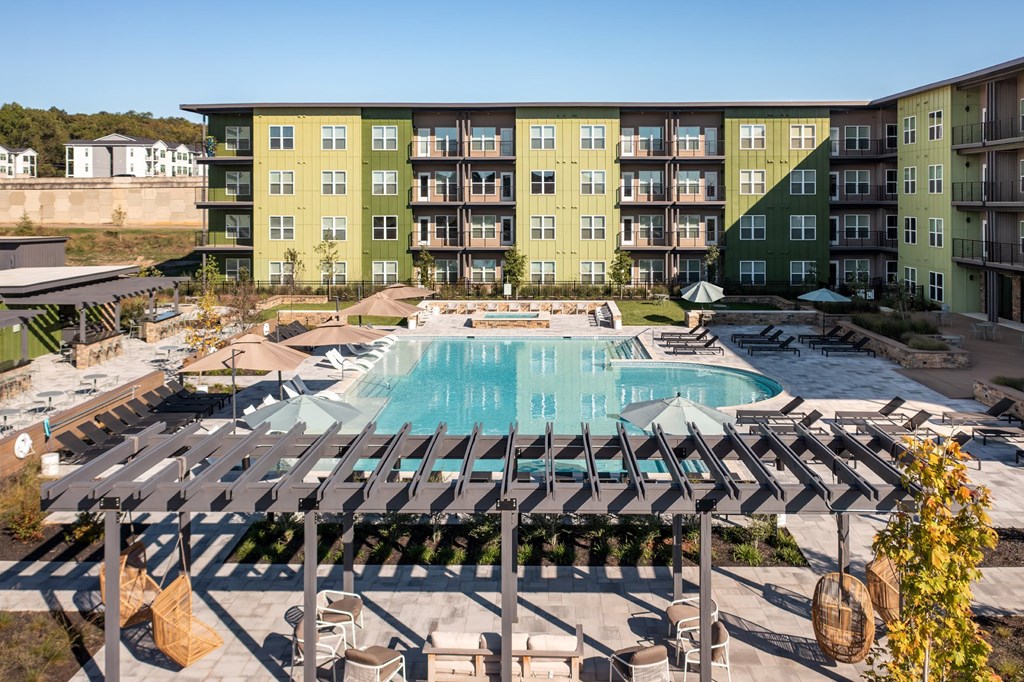 A large swimming pool surrounded by a shaded area with sun loungers.