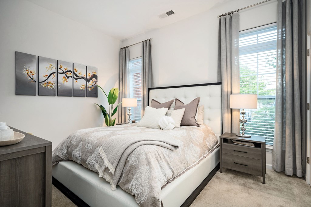 A bedroom with a large bed and a plant on the side table.