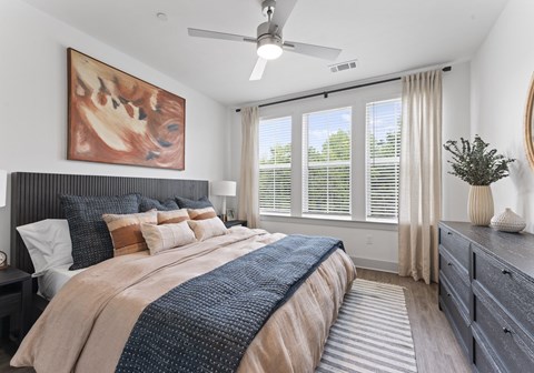A bedroom with a large bed and a ceiling fan.