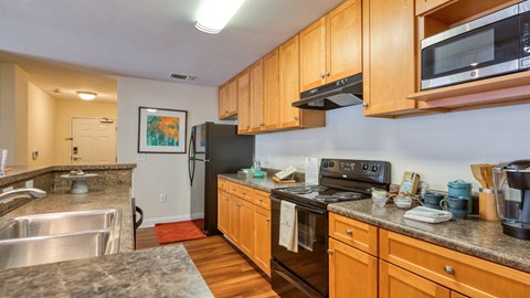 A kitchen with wooden cabinets and a black refrigerator.